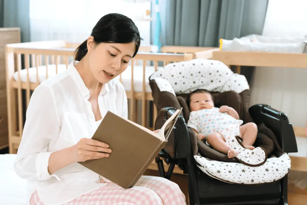 new mom sitting next to her baby finding time to read a book