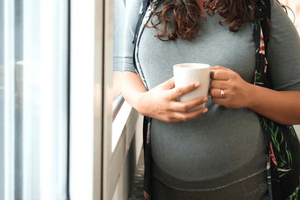 pregnant woman holding a cup of coffee in her hand