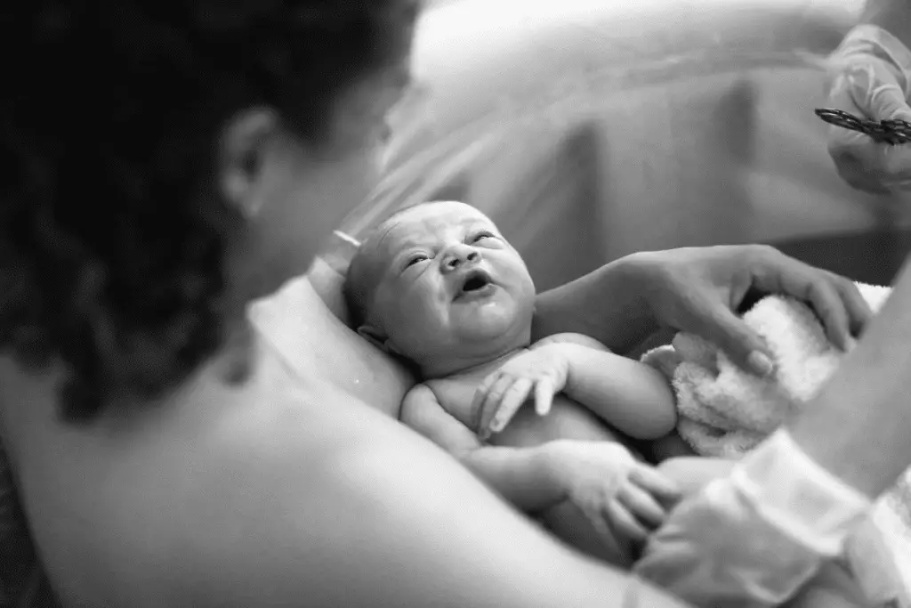 woman holding her newborn right after having given birth