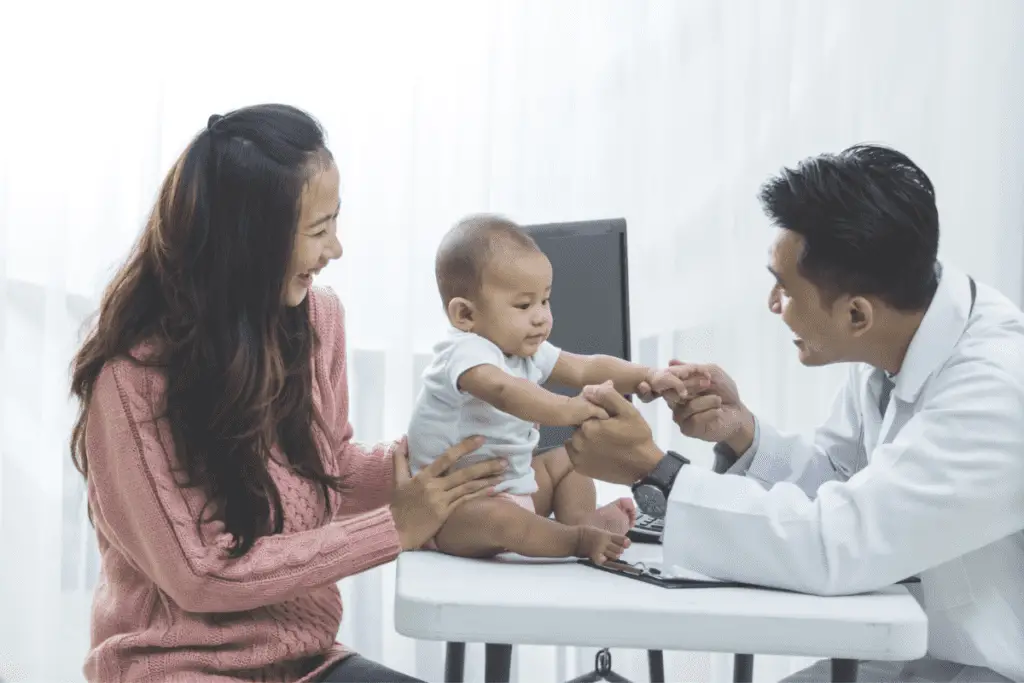 a pediatrician examining a baby held by his mother