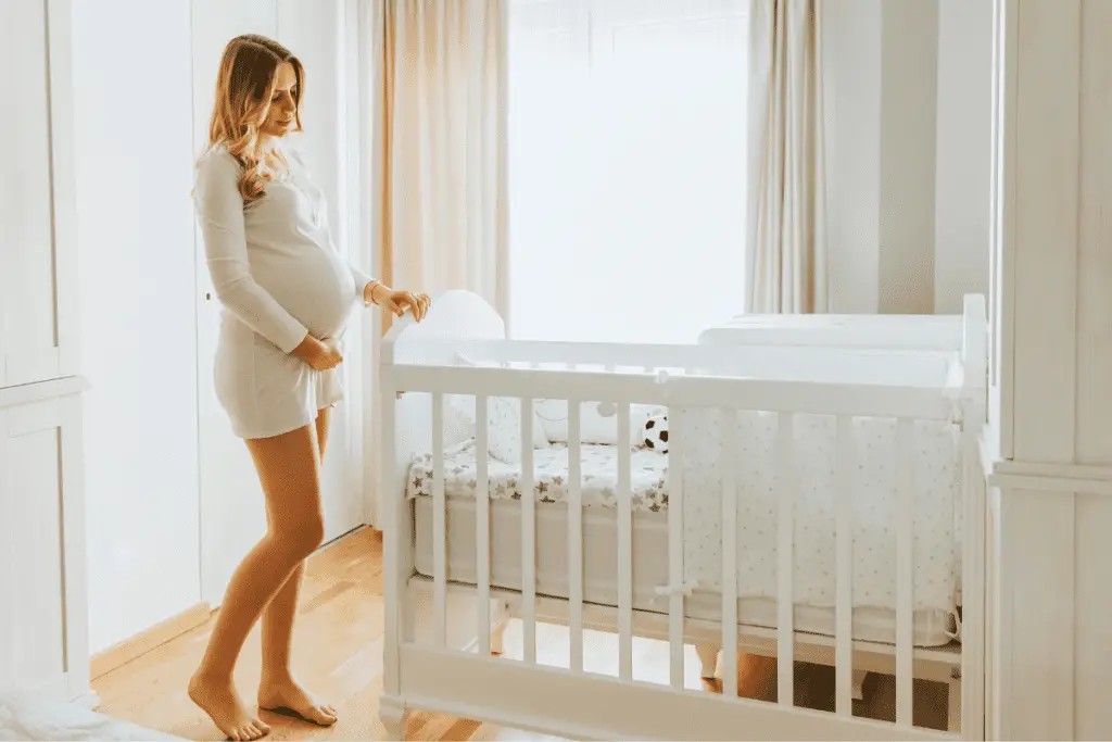pregnant woman standing in the nursery holding her pregnant belly