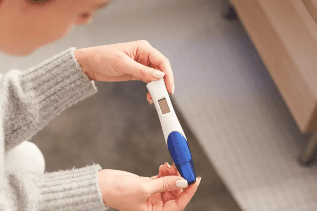 woman holding a pregnancy test studying how it works before using it